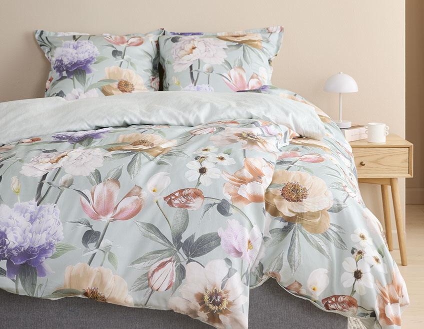 Bettwäsche mit floralem Muster in einem hellen Schlafzimmer