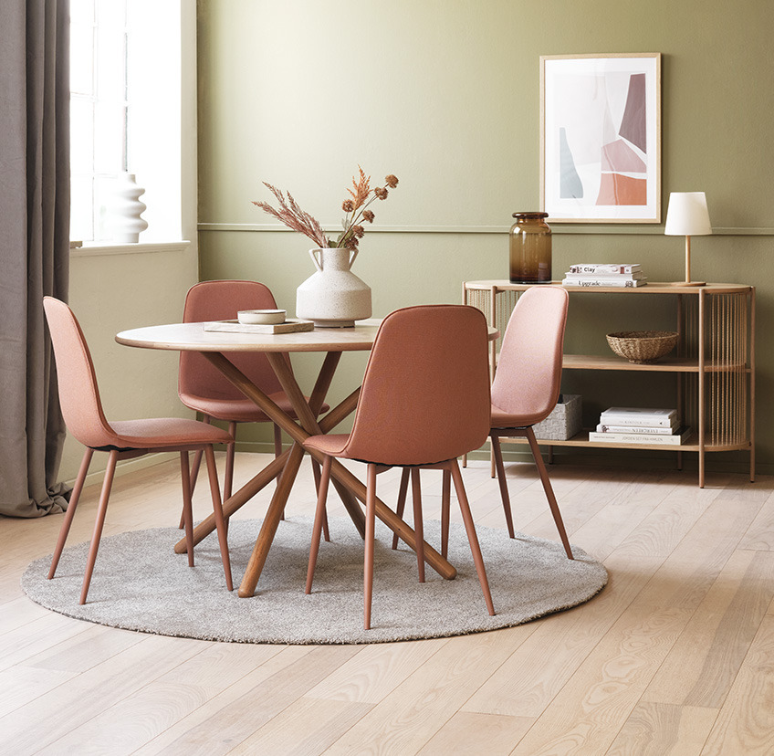 Chaises de salle à manger en pêche/corail autour d'une table à manger ronde dans le salon