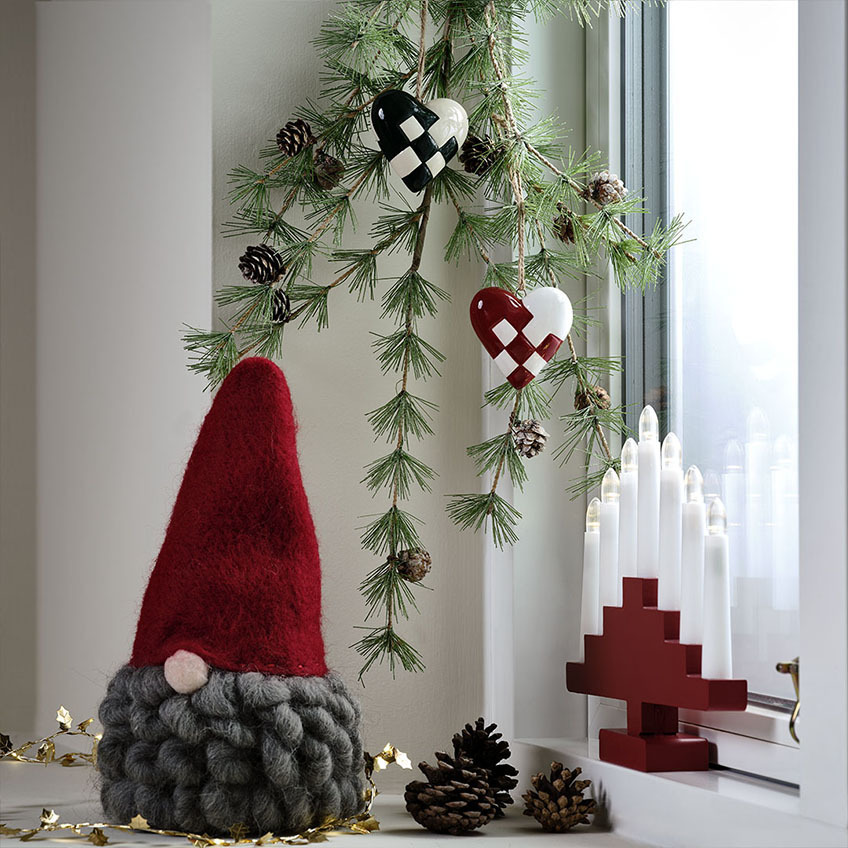 Lutin de Noël avec un bonnet rouge et une barbe grise, décoration de cœur de Noël et arche de bougies rouges