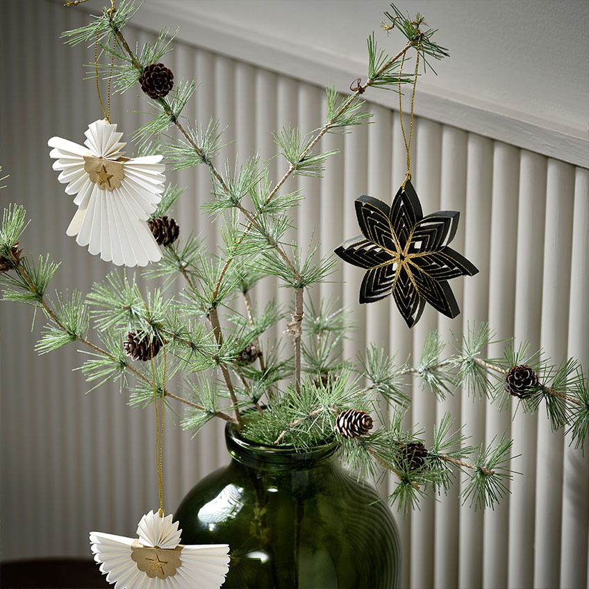 Des branches de sapin avec une décoration dans un vase décoré à la scandinave