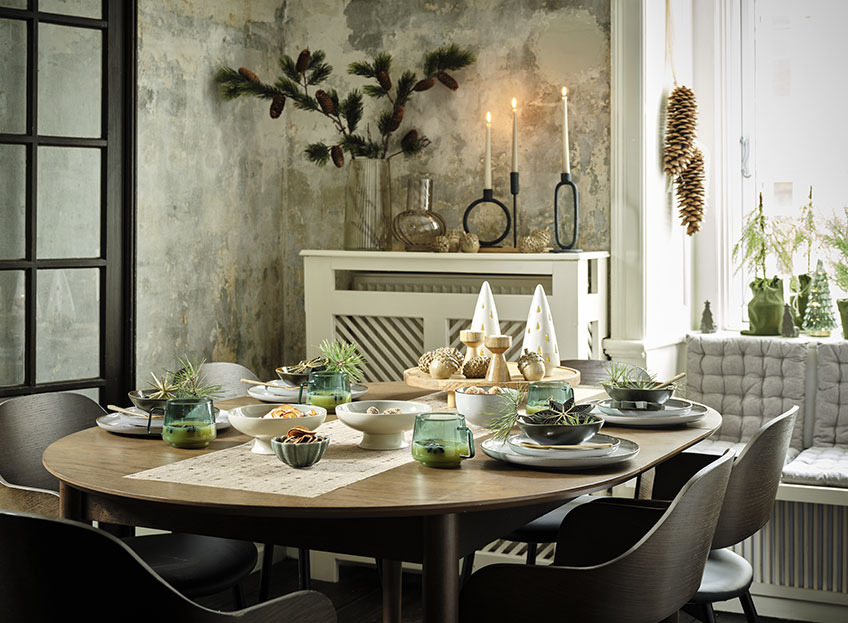 Table dressée dans la salle à manger avec chemin de table de Noël, assiettes, bols et décorations de Noël