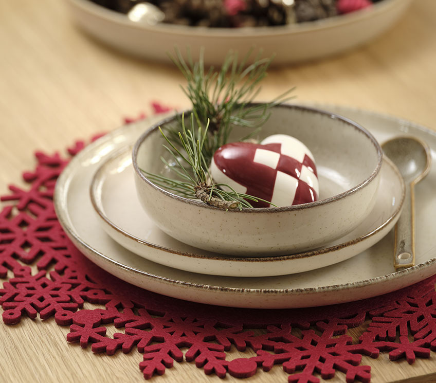 Tovaglietta rossa con piatti, ciotola e decorazioni.