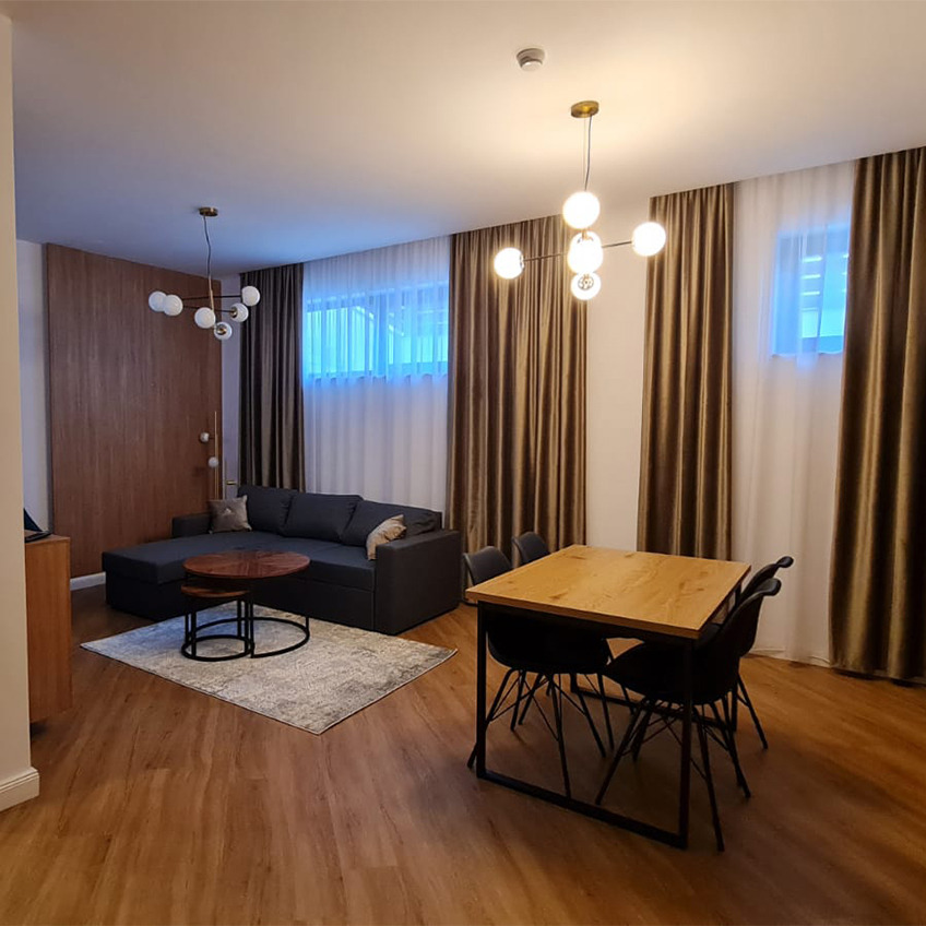 Esstisch AABENRAA, Esszimmerstühle KLARUP und Couch MARSLEV Möbliertes Wohnzimmer mit Tisch, Couch und Dekoration