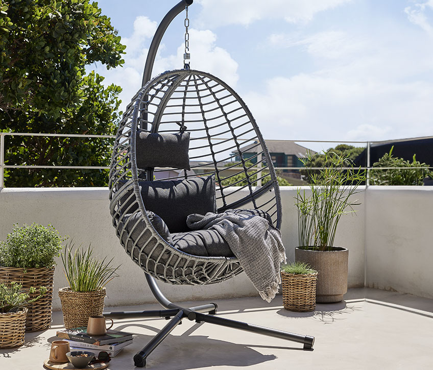 Chaise suspendue grise sur une terrasse ensoleillée