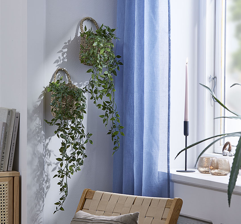 Due cesti con piante artificiali appesi a una parete del soggiorno.