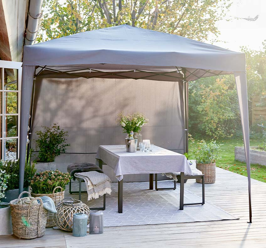 Grauer Gartenpavillon mit abnehmbaren Seitenwänden auf der Terrasse im hinteren Garten