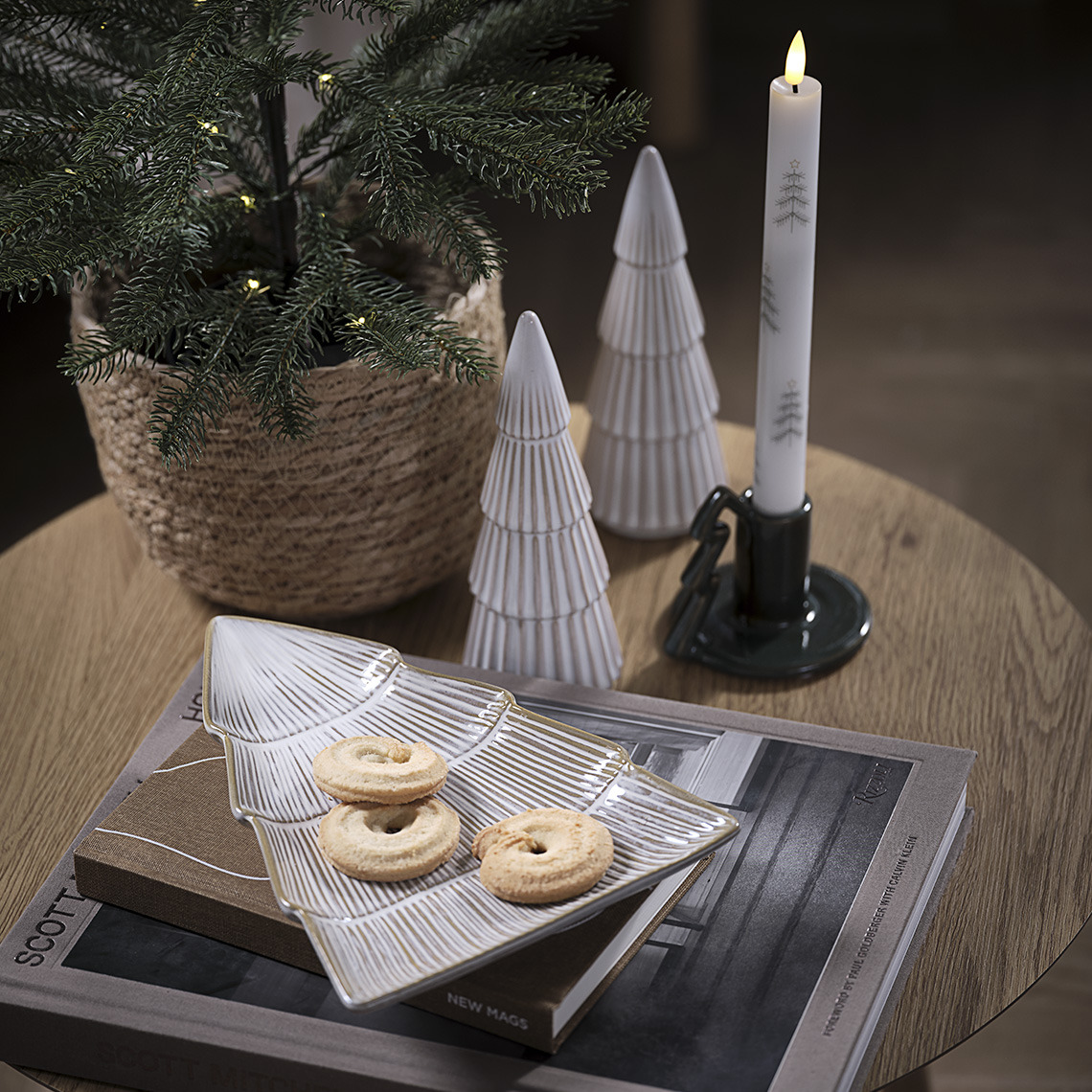 Vassoio decorativo con biscotti, due alberi decorativo e portacandele con candela su una tavola