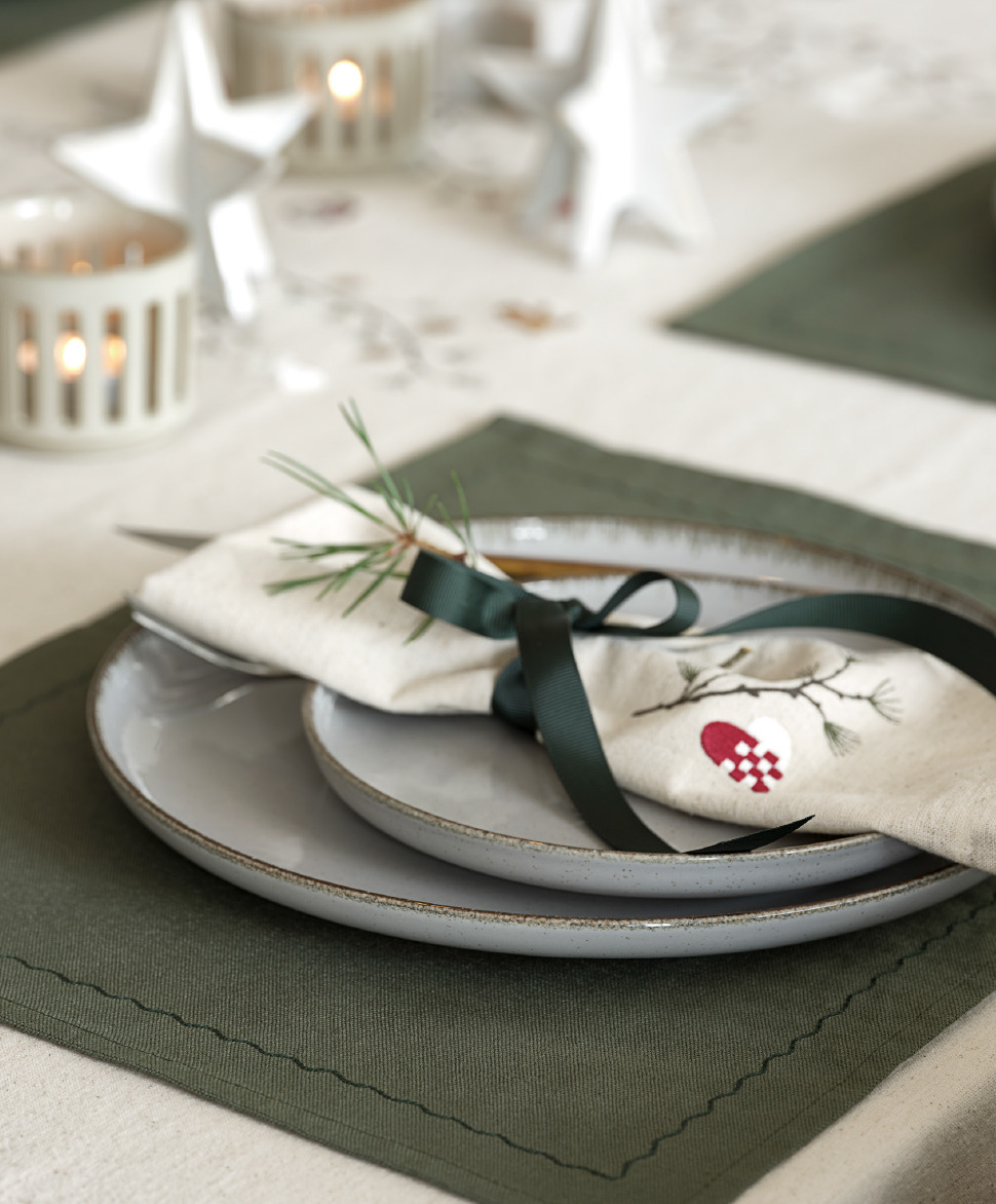 Serviette en tissu NELLIKE avec broderie de Noël Serviette soigneusement pliée sur une assiette