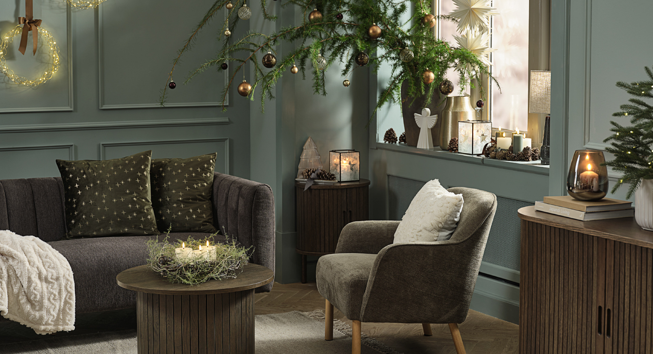Coussins décoratifs ALVALDE et NJORD, buffet LYNGVIG et couronne de Noël SNE Un salon peint en vert décoré pour Noël