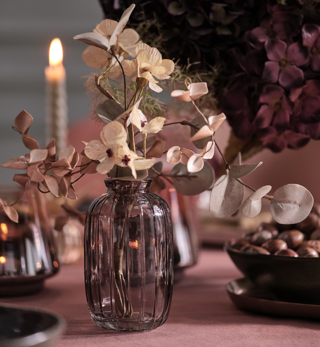 Graue Glasvase mit künstlichen Blumen auf einem Tisch