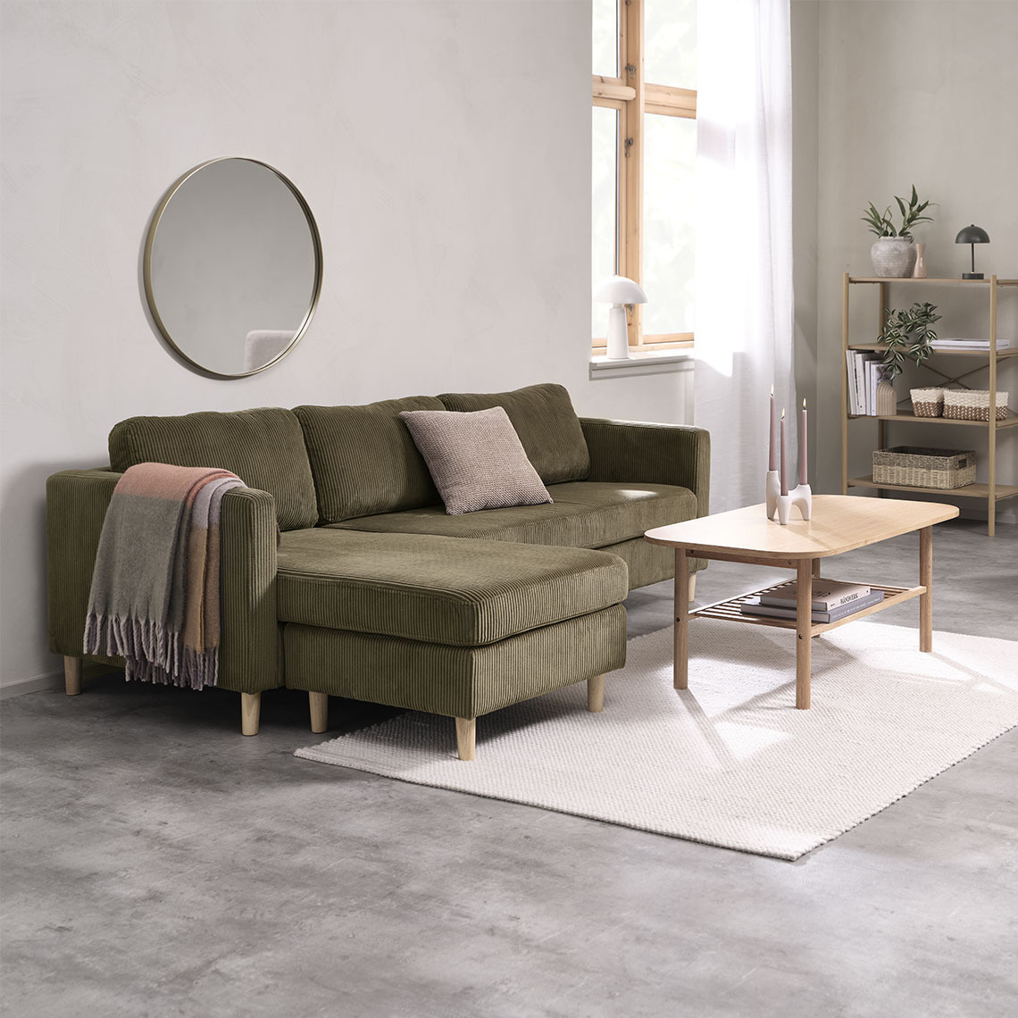 Olivgrünes Chaiselounge-Sofa mit Couchtisch und bunten Decken und Kissen