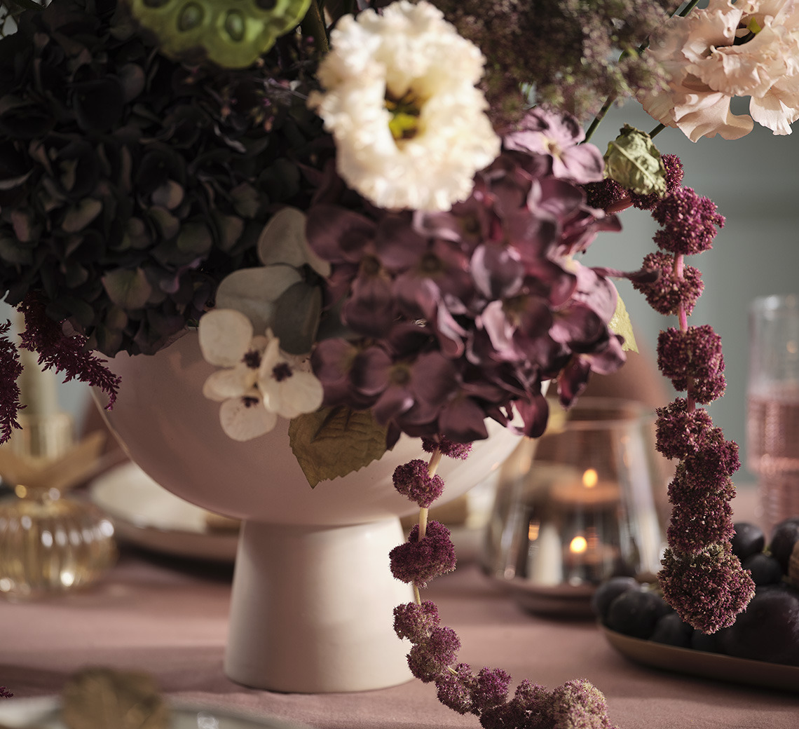 Bol avec fleurs artificielles sur une table de salle à manger festive