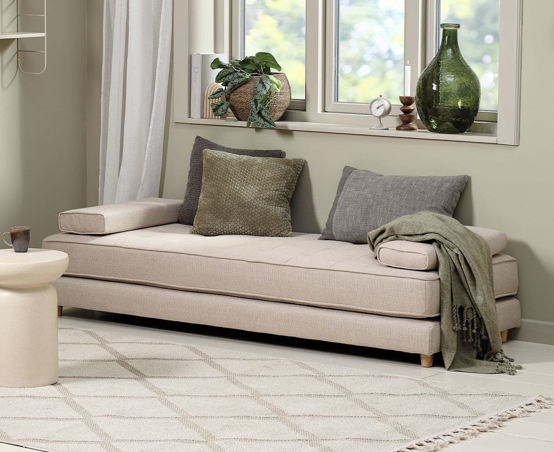 Divanetto beige in soggiorno con cuscini e coperta