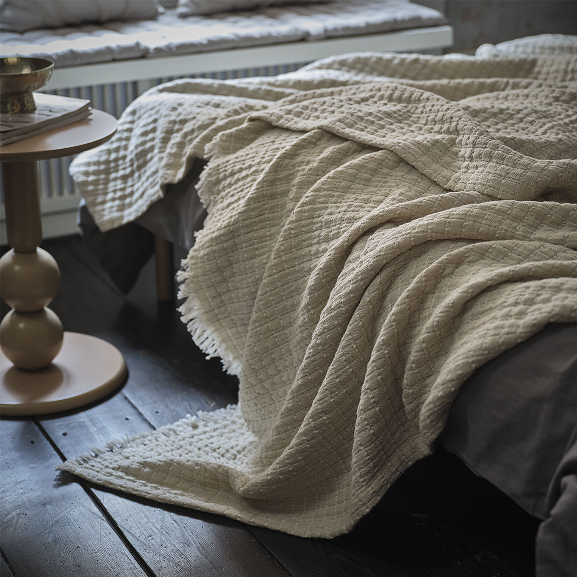 Eine beige Decke auf einem Bett in einem Schlafzimmer.