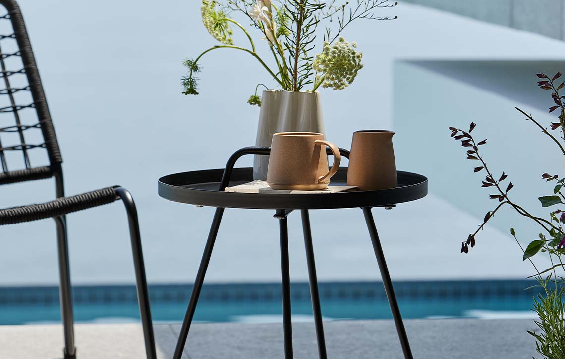 Table d'appoint en acier sur une terrasse à côté d'une piscine