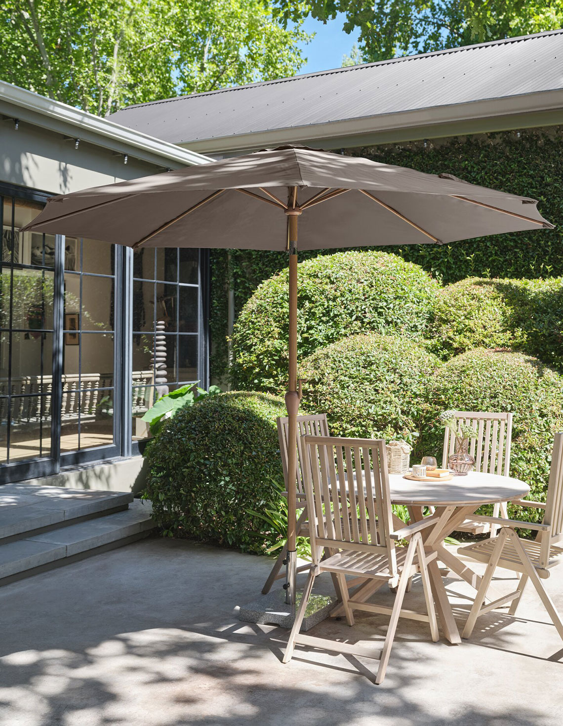 Grosser beiger Sonnenschirm auf der Terrasse mit Gartentisch und Gartenstühlen