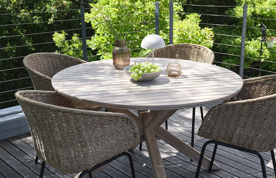 Table de jardin en acacia massif sur une terrasse avec chaises de jardin en polyrotin et acier