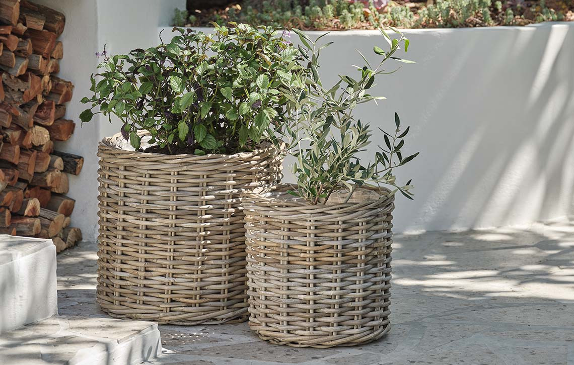 Bacs à fleurs en rotin tressé sur une terrasse