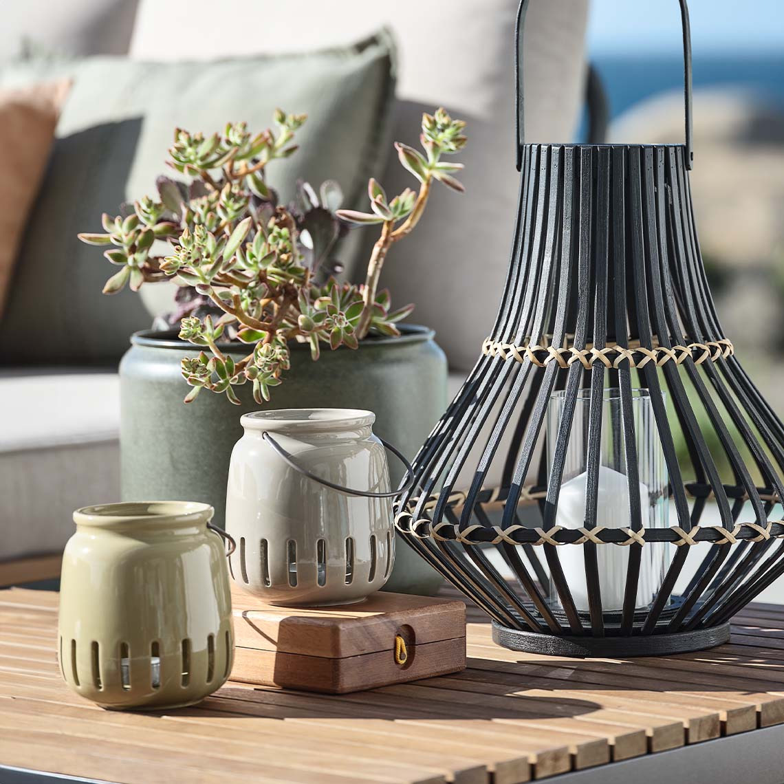  Gartenlaternen in verschiedenen Materialien und Grössen auf einem Lounge-Tisch im Freien