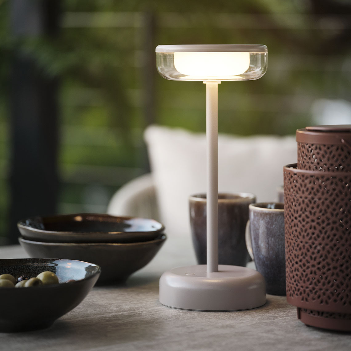  Batteriebetriebene Tischlampe auf einem Gartentisch mit Schüsseln und Bechern