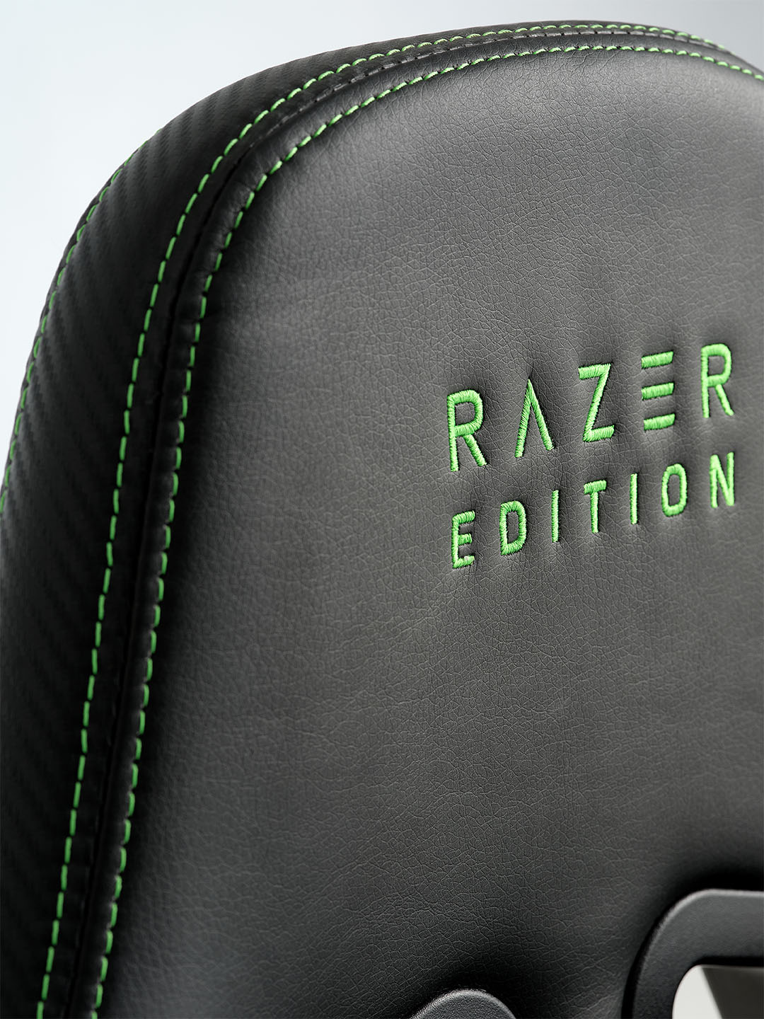 TYPE Z – RAZER EDITION™ BY LEGEND Gaming-Stuhl Nahaufnahme eines schwarzen Razer-Gaming-Stuhls mit grünen Nähten und grün gesticktem Schriftzug „RAZER EDITION“ auf der Rückenlehne.
