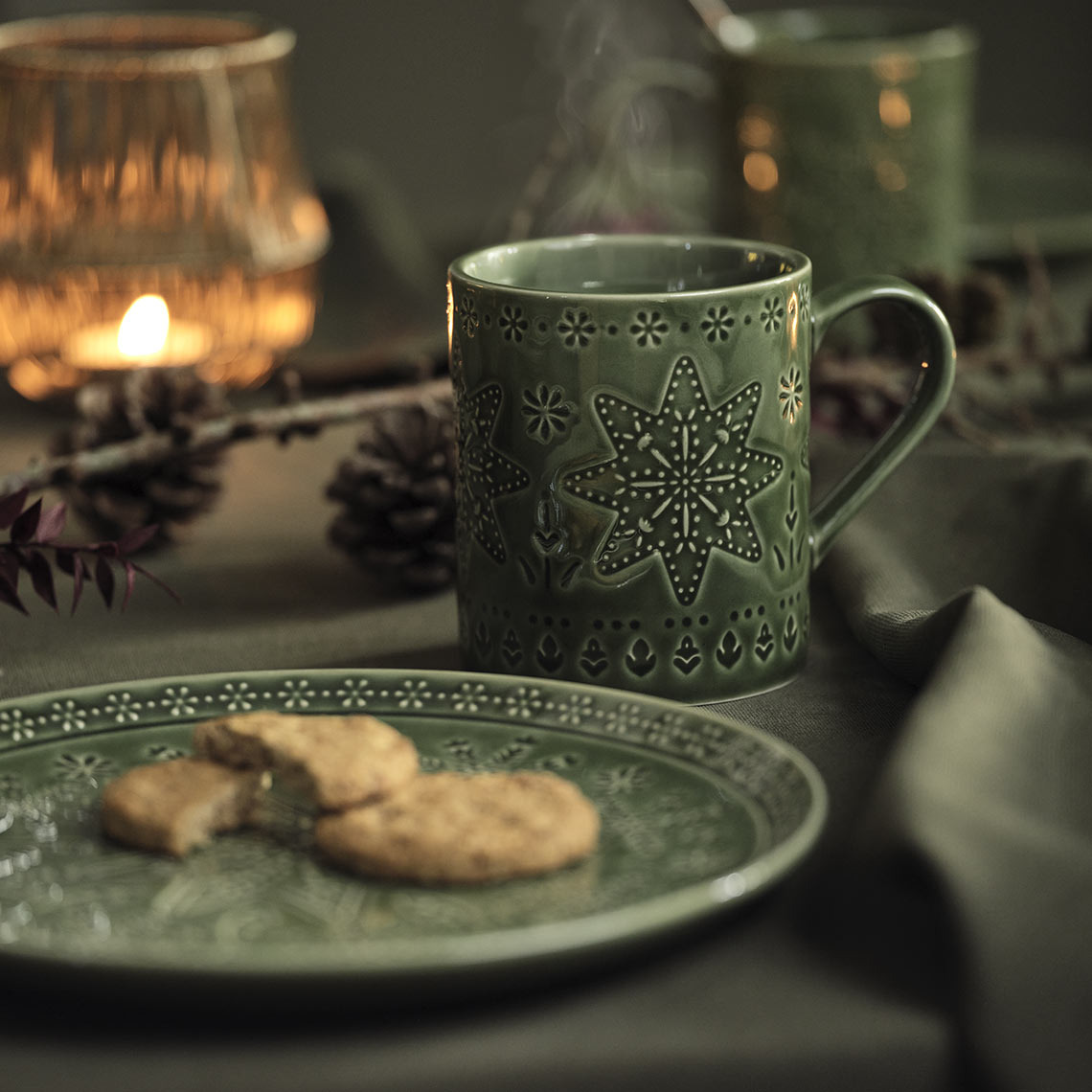 Grüner Weihnachts-Teller und Tasse auf festlich gedecktem Tisch