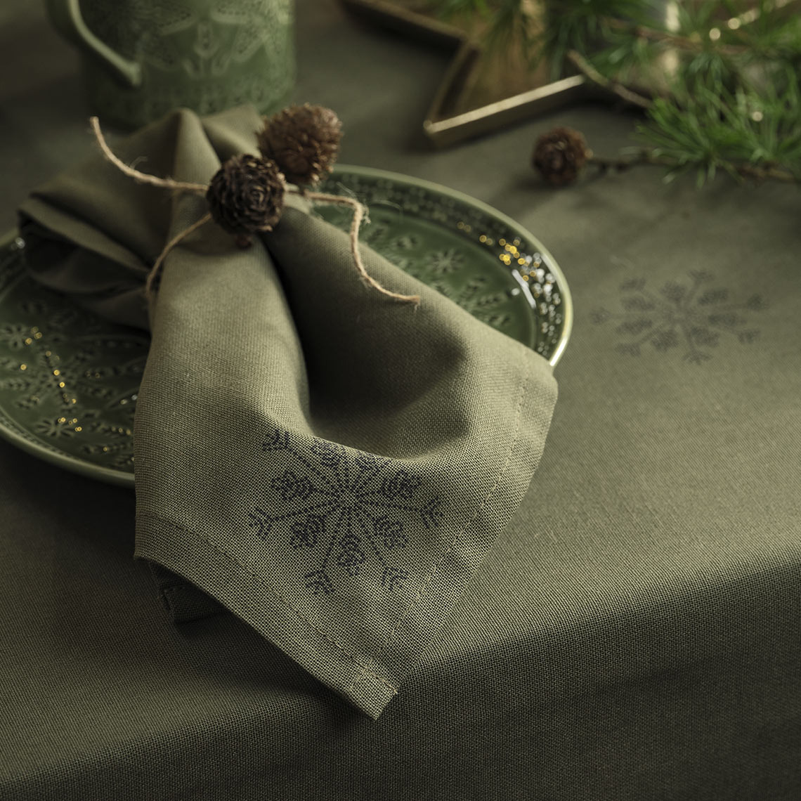 Grüne Weihnachts-Tischdecke und Weihnachts-Stoffserviette auf einem grünen Teller
