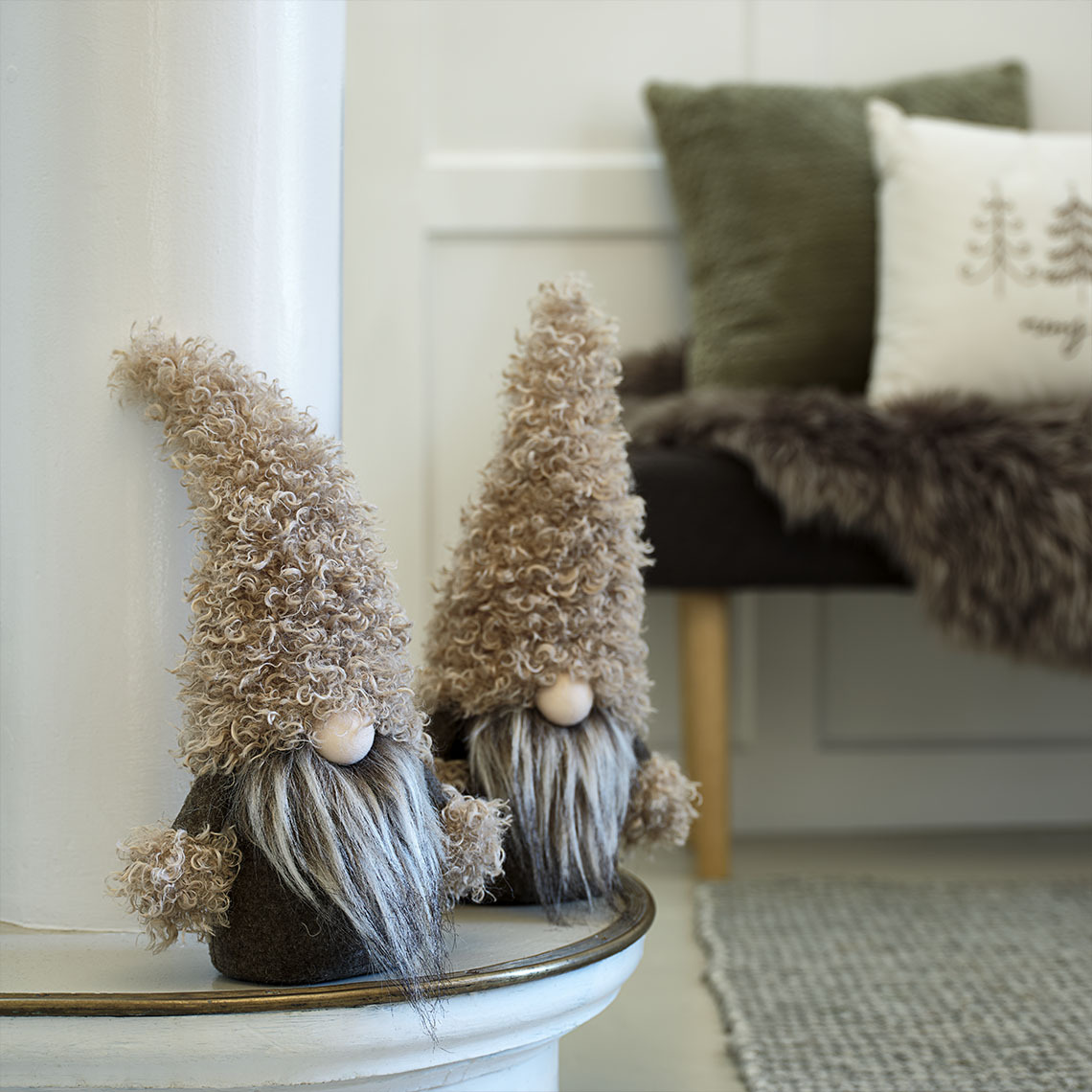 Elfi natalizi decorativi nei toni del marrone e del verde su una credenza