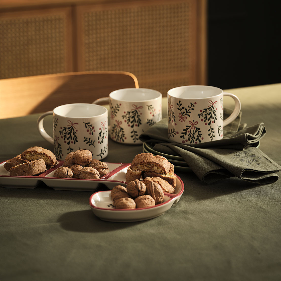 Tazze natalizie LIN, ciotola natalizia LIN e tovagliolo in tessuto STJERNESTEN Tazze e ciotola natalizie con tovaglioli in tessuto a tema Natale sul tavolo.