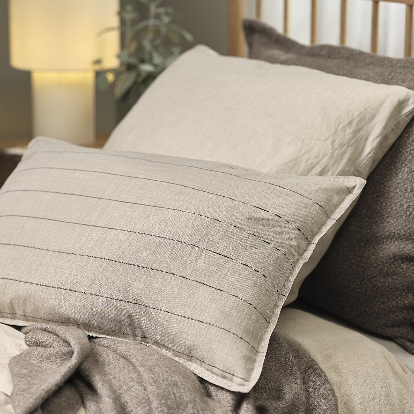 Fodera per cuscino decorativo POPPEL color sabbia con strisce marroni Cuscino su un letto