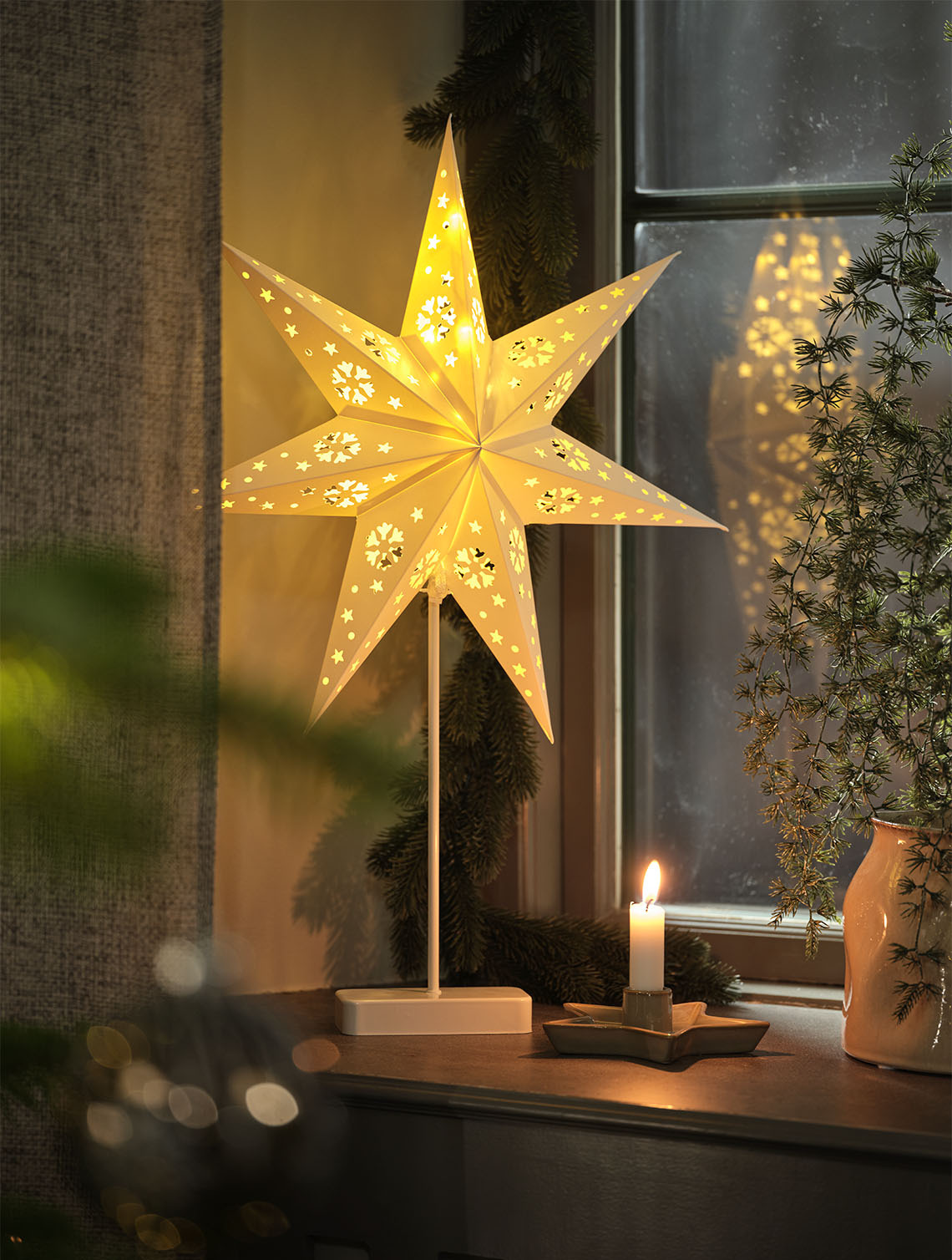 Étoile de Noël UNAKIT avec minuterie intégrée Une étoile de Noël lumineuse qui éclaire une fenêtre à l'intérieur d'une maison