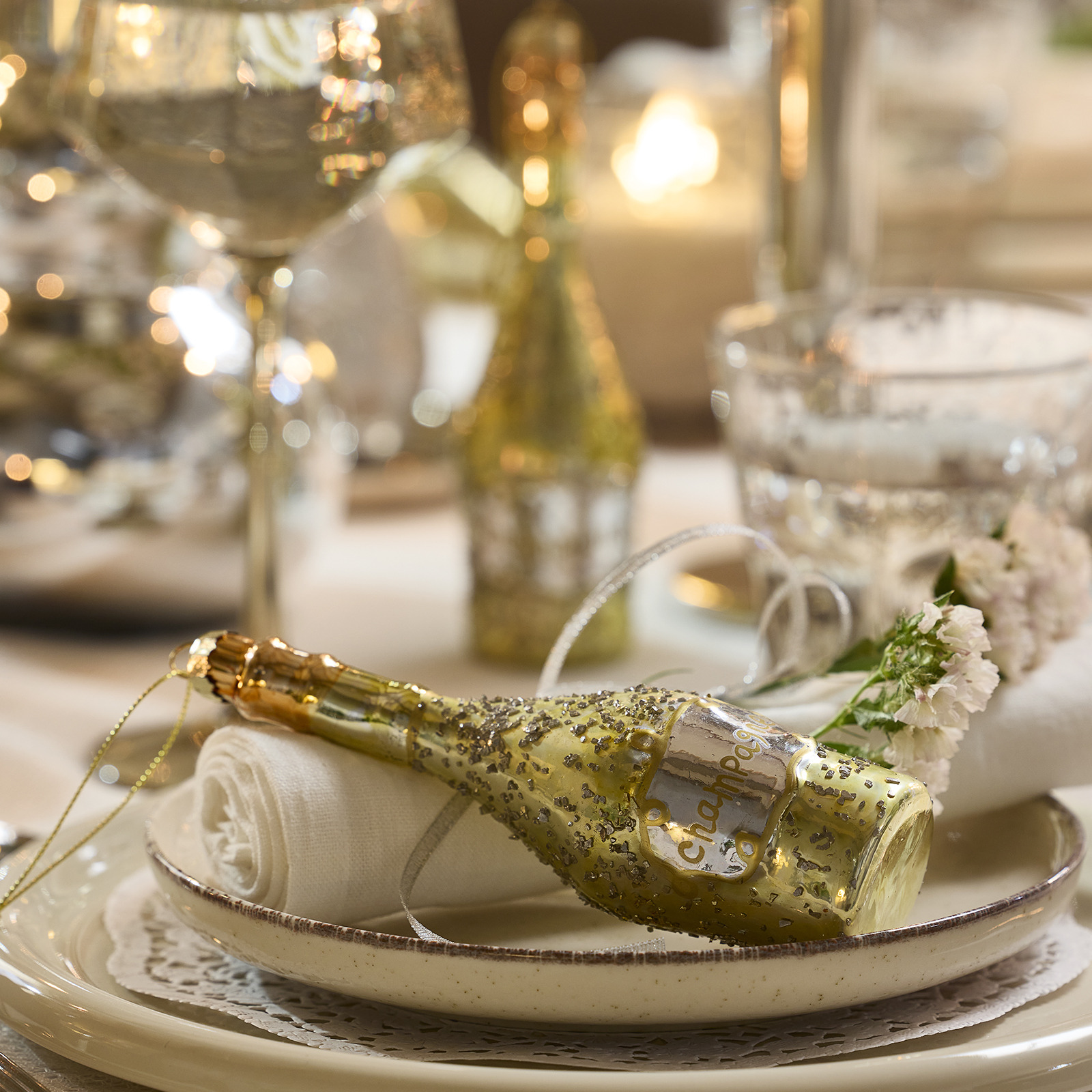 Gedeckter Tisch mit einer weihnachtlichen Baumdekoration in Form einer Champagnerflasche