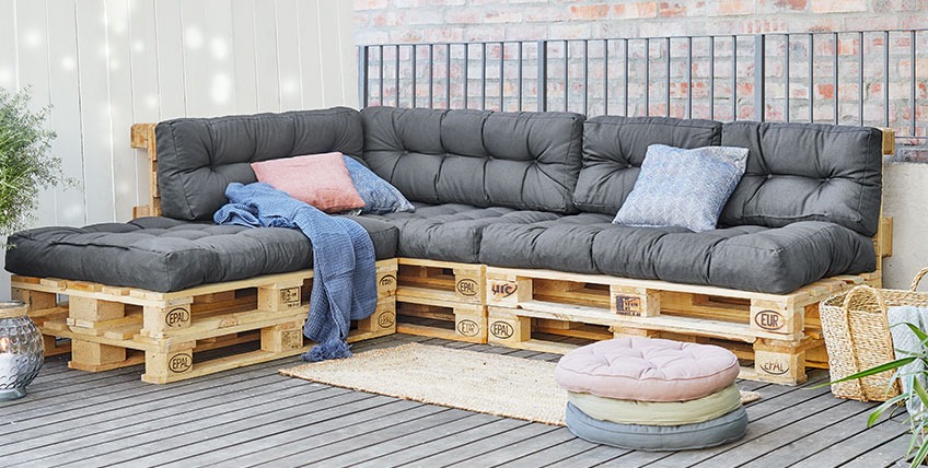 Grosses Paletten-Ecksofa mit verlängertem Ende auf einer Terrasse