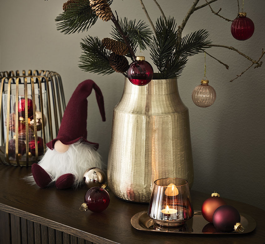 Goldener Kerzenständer, Weihnachtswichtel und goldene Vase mit Fichtenzweigen und Weihnachtskugeln 