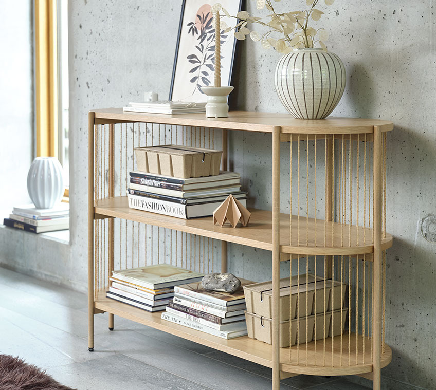 Das Sideboard EGELEV ist auch in Schwarz erhältlich Wohnzimmer mit einem Sideboard aus heller Eiche mit einer Vase und Büchern sowie Aufbewahrungsboxen
