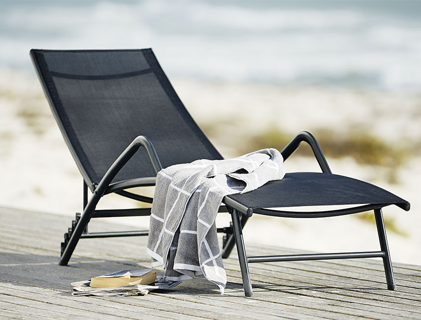 Lettino in legno con appoggia braccie su terrazza affacciata al mare