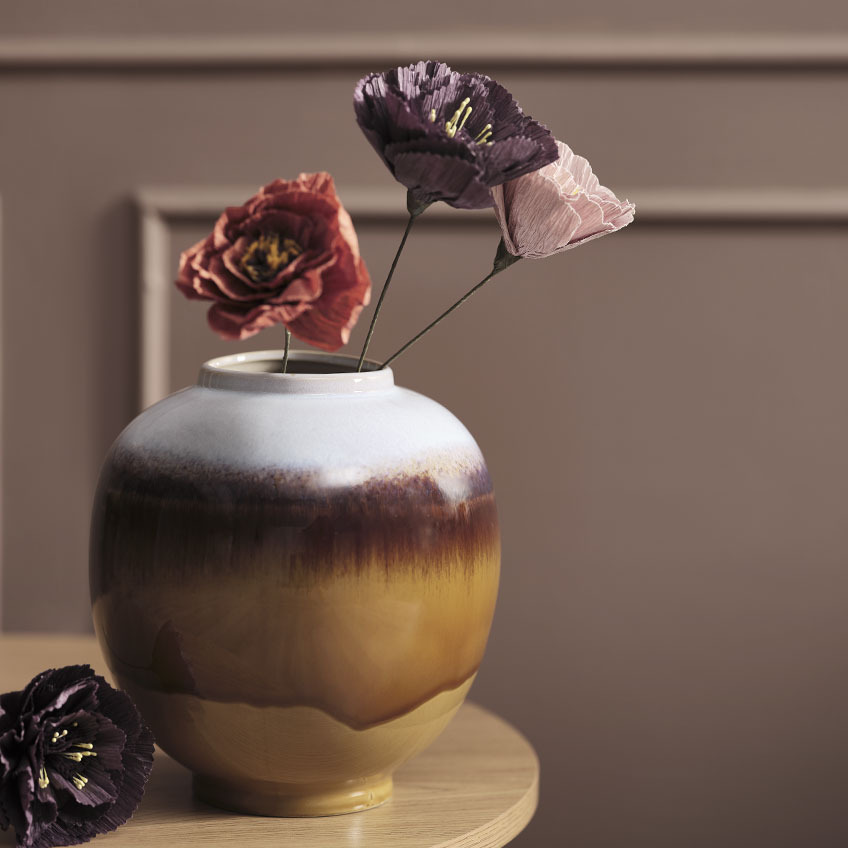 Vaso multicolore con fiori artificiali rossi, viola e rosa su un tavolino