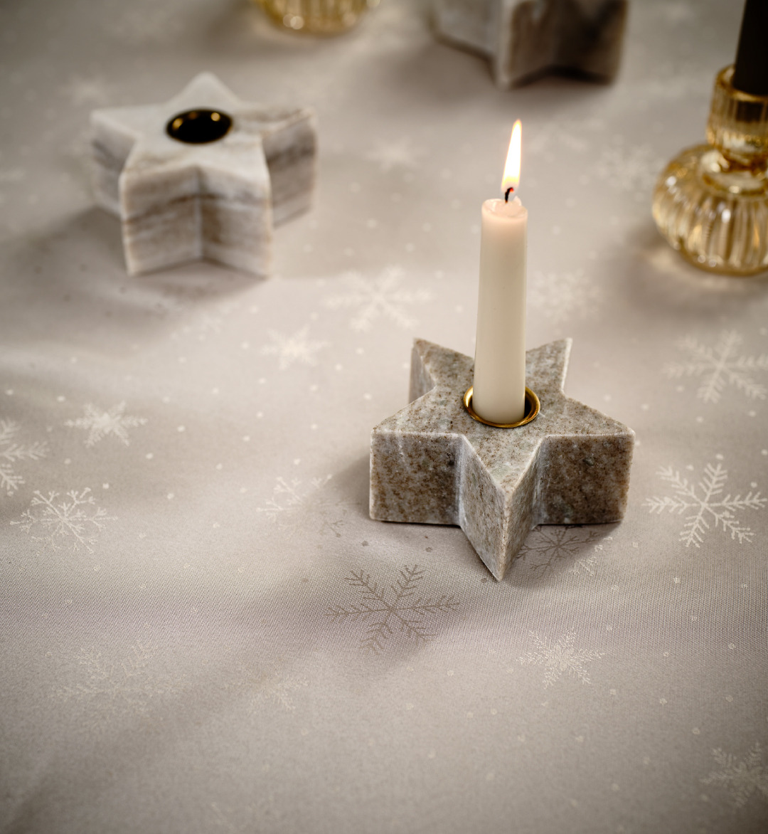 Tavolo con candelabri a forme di stelle e candela bianca pronto per il Natale